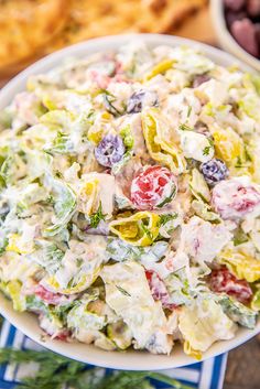 a white bowl filled with salad next to olives and bread