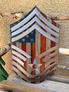 a wooden shield with an american flag design on it sitting on a bench next to a wall