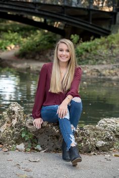 a woman sitting on top of a rock next to a river