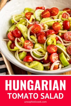 a white bowl filled with tomatoes, onions and cucumber on top of a wooden table