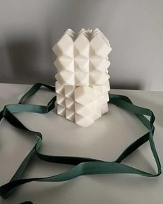 a white sculpture sitting on top of a table next to a green ribbon tied around it