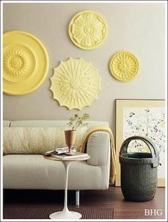 a living room with white furniture and yellow plates on the wall above it's coffee table