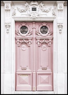 two pink doors with ornate carvings on the front and side of a large white building