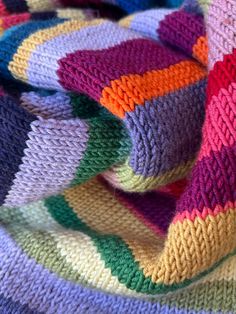 a multicolored knitted blanket laying on top of each other