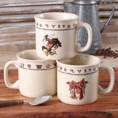 three coffee mugs sitting on top of a wooden table next to a tea pot