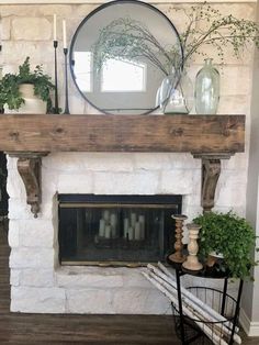 a fireplace with some potted plants on top of it and a mirror above the fire place