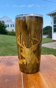 a wooden cup sitting on top of a wooden table next to a grass covered field