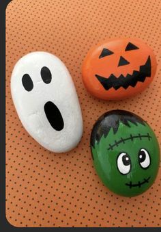 three rocks with faces painted on them sitting next to each other in front of a polka dot background