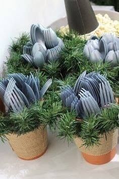 there are many plastic utensils in small pots on the table with pine needles