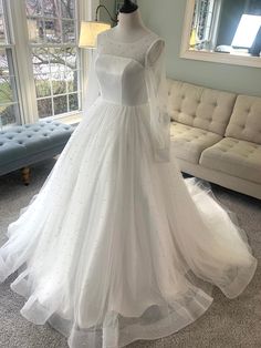 a white wedding dress on display in front of a large window with lots of windows