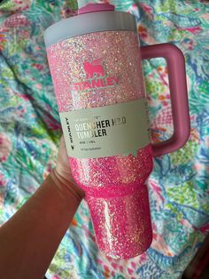 a person is holding a pink and silver glittered tumbler with the lid up