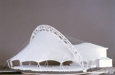 a model of a white building on top of a wooden table next to a gray wall