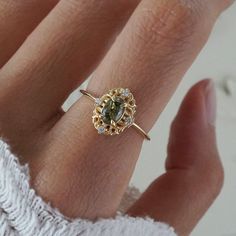 a woman's hand with a ring on it and a green stone in the middle