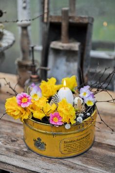 a tin can with flowers and candles in it