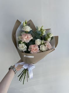 a hand holding a bouquet of white and pink flowers