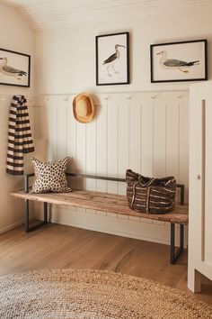 a wooden bench sitting in the middle of a room next to pictures on the wall