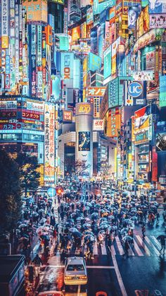 many people with umbrellas are crossing the street in front of tall buildings at night