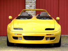 a yellow sports car parked in front of a red building