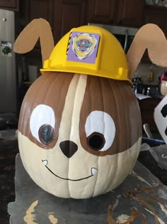 a large pumpkin with a construction helmet on it's head and eyes painted to look like a dog