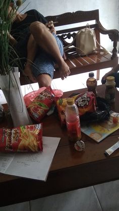 a person sitting on a bench with some food and drinks in front of them,