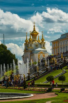 people are walking around in front of a large building with gold domes on it's steeple