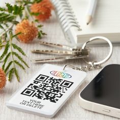 a qr code keychain sitting on top of a desk next to a cell phone