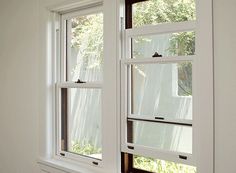 two windows in a room with white walls and wood trimming on the window sill