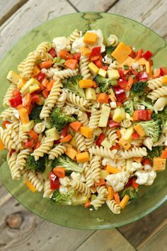 a bowl filled with pasta salad on top of a wooden table