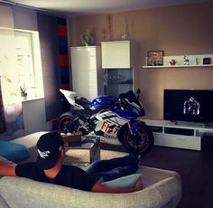 a man sitting on a couch in front of a tv with a motorcycle parked next to it