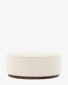 a white round ottoman sitting on top of a wooden table