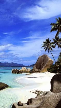 an island with rocks and palm trees on the beach