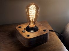 a light bulb sitting on top of a wooden table next to a lamp plugged in