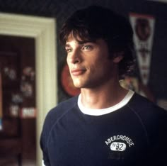 a young man standing in front of a doorway wearing a black and white t - shirt