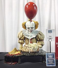 a statue of a clown with a red balloon on top of it's head