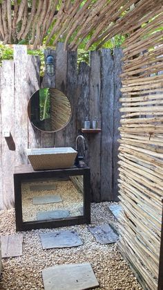 a bathroom with a sink, mirror and wood fenced in area that has stones on the ground