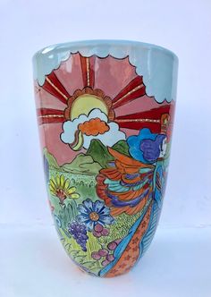 a colorful vase is sitting on a white surface with flowers and birds painted on it