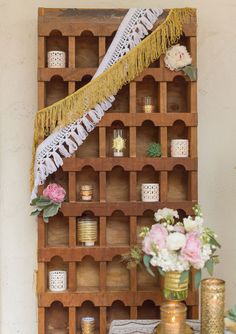 a wooden shelf filled with candles and flowers on top of a white table next to a vase