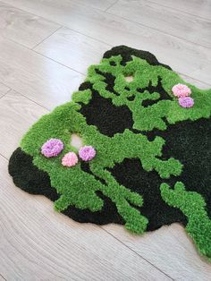 a green rug with pink flowers on top of the floor in front of a white wooden floor