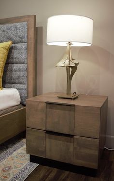 a nightstand with a lamp on it next to a bed