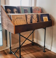 a wooden table topped with lots of books on top of a hard wood floor next to a window