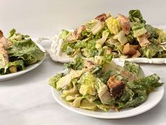 two white plates filled with salad on top of a table