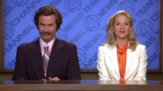 a man and woman sitting at a table in front of a blue screen with the news logo on it