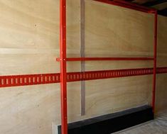 the inside of a storage room with red shelves and metal bars on each side of the wall