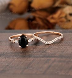 two black and white diamond wedding rings sitting on top of a wooden table with stuffed animals in the background