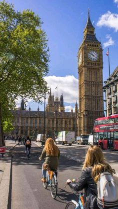 two women riding bicycles down the street in front of big ben