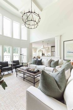 a living room filled with furniture and a chandelier hanging over the fire place