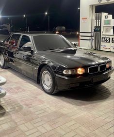 a black car parked in front of a gas station at night with no one around it