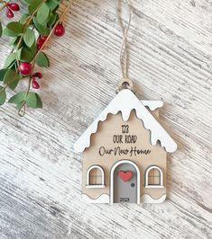 a christmas ornament hanging on a wooden table next to holly branches and red berries