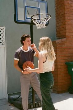 a man standing next to a woman holding a basketball