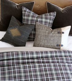 a bed with plaid pillows and blankets on it